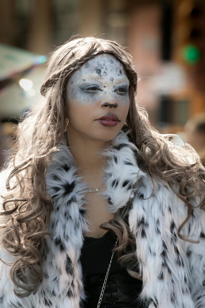 Stylish woman in unique makeup and fur coat captured in New York City street setting.